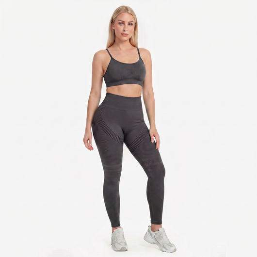 Woman wearing a gray sports bra and leggings set on a white background